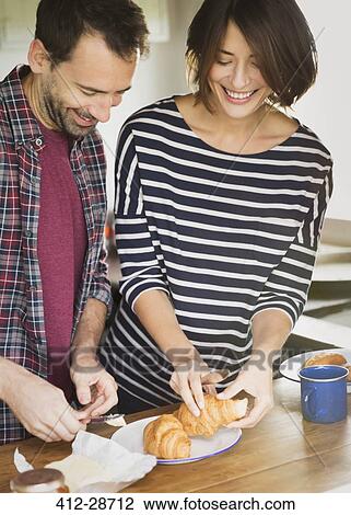 Couple buttering croissants View Large Photo Image Stock Image - Couple buttering croissants. Fotosearch