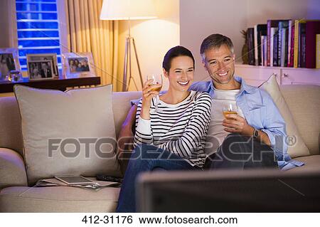 Couple drinking wine and watching TV in living room View Large Photo Image Stock Photograph - Couple drinking wine and watching TV in living room. Fotosearch