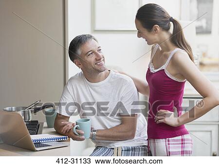 Couple in pajamas talking and drinking coffee at laptop View Large Photo Image Stock Image - Couple in pajamas talking and drinking coffee at laptop. Fotosearch