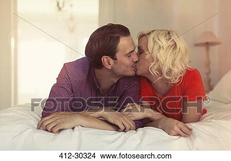 Picture - Couple kissing on bed. Fotosearch