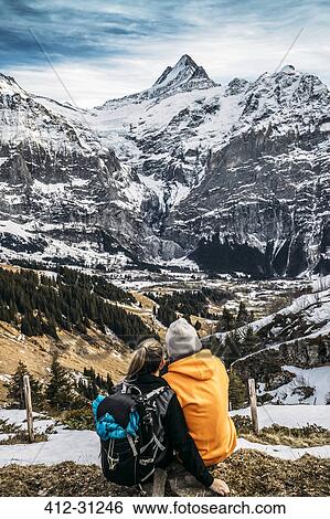 Couple looking at snowy mountain view, Grindelwald, Switzerland View Large Photo Image Stock Photograph - Couple looking at snowy mountain view, Grindelwald, Switzerland. Fotosearch