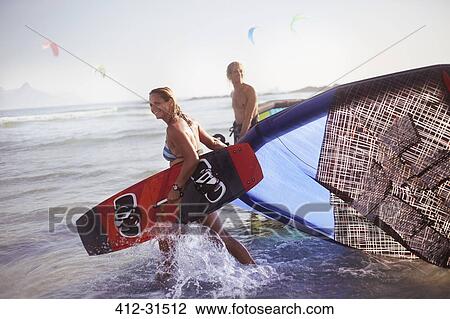 Couple pulling kiteboarding equipment into ocean surf View Large Photo Image Stock Image - Couple pulling kiteboarding equipment into ocean surf. Fotosearch