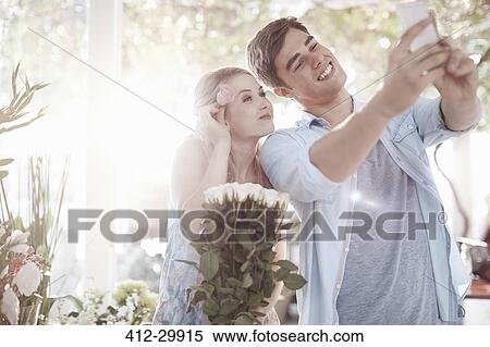 Stock Photography - Couple taking selfie at flower shop. Fotosearch