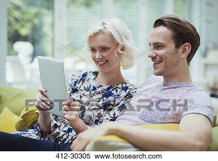Couple using digital tablet on living room sofa View Large Photo Image Stock Photography - Couple using digital tablet on living room sofa. Fotosearch