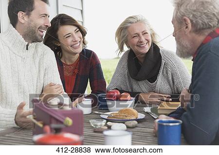 Stock Photo - Couples talking and enjoying breakfast at patio table. Fotosearch