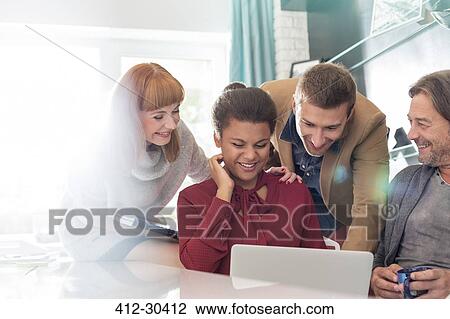 Stock Image - Creative business people sharing laptop in meeting. Fotosearch