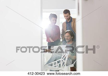 Stock Image - Creative business people sharing laptop in office meeting. Fotosearch