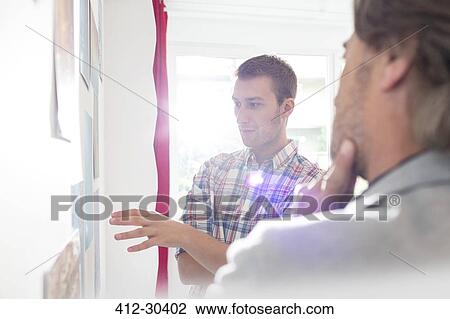 Creative businessmen brainstorming at board in office View Large Photo Image Stock Image - Creative businessmen brainstorming at board in office. Fotosearch