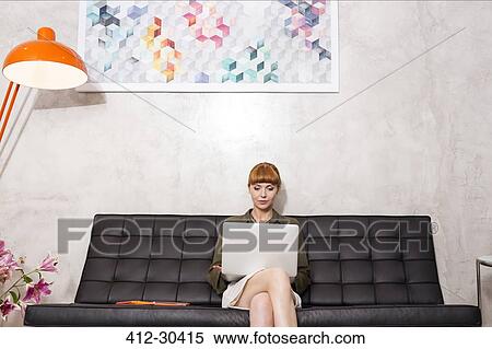 Stock Photography - Creative businesswoman using laptop on sofa. Fotosearch