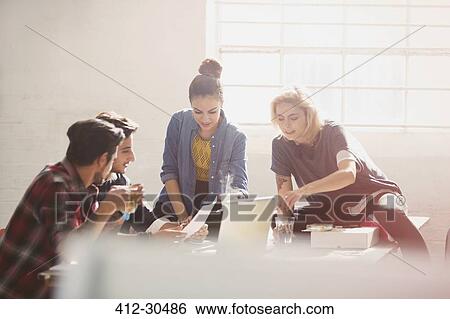 Creative young business people brainstorming at laptop in sunny office View Large Photo Image Stock Photograph - Creative young business people brainstorming at laptop in sunny office. Fotosearch