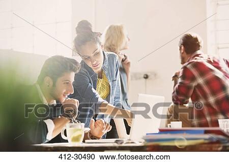 Creative young business people working at laptop in office View Large Photo Image Stock Image - Creative young business people working at laptop in office. Fotosearch