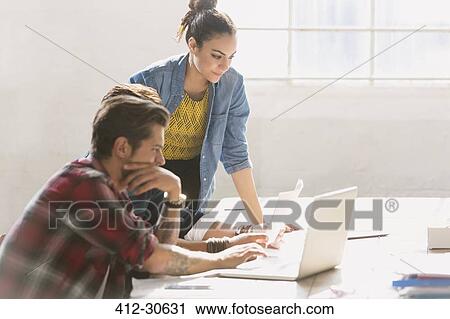 Creative young business people working at laptop in sunny office View Large Photo Image Stock Image - Creative young business people working at laptop in sunny office. Fotosearch