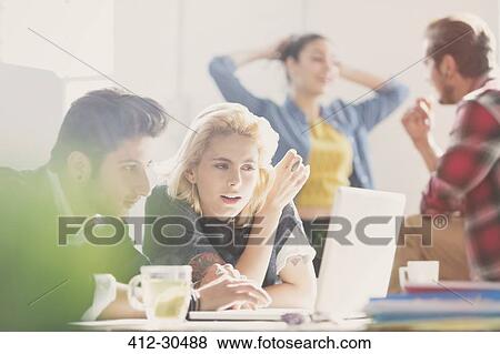 Creative young business people working at laptop in office View Large Photo Image Stock Photo - Creative young business people working at laptop in office. Fotosearch