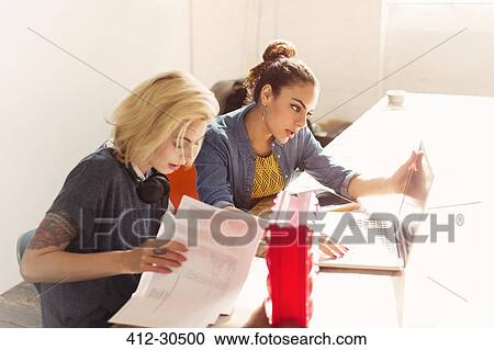 Creative young businesswomen with laptop and paperwork in office View Large Photo Image Stock Image - Creative young businesswomen with laptop and paperwork in office. Fotosearch
