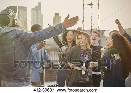 Stock Photo - Crowd cheering for DJ at rooftop party. Fotosearch
