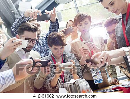 Stock Image - Crowd using camera phones at technology conference. Fotosearch