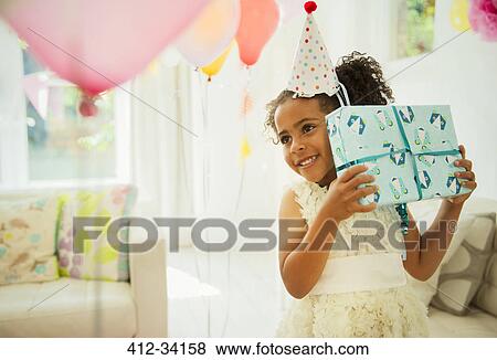 Curious girl shaking birthday gift View Large Photo Image Stock Photo - Curious girl shaking birthday gift. Fotosearch
