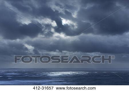 Stock Photo - Dark clouds in overcast sky over ocean, Devon, United Kingdom. Fotosearch