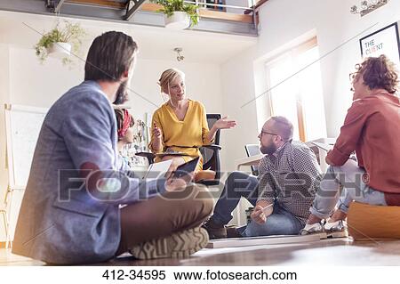 Stock Photography - Design professionals meeting sitting on floor. Fotosearch
