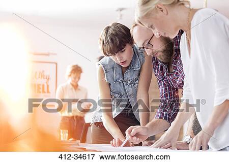 Stock Photo - Design professionals reviewing proofs in office. Fotosearch
