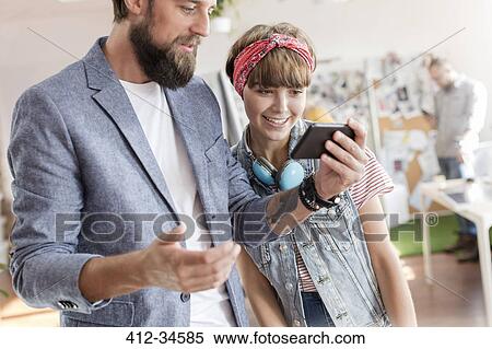 Stock Photography - Design professionals using cell phone in office. Fotosearch