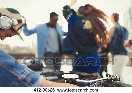 Stock Photograph - DJ spinning records at rooftop party. Fotosearch
