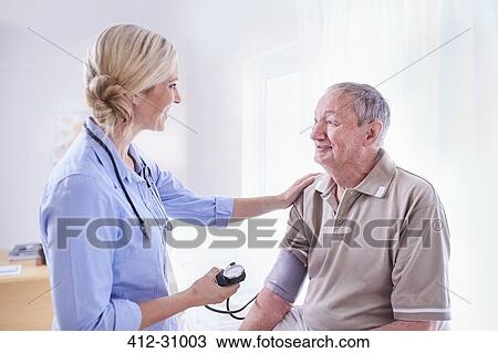 Stock Image - Doctor checking senior mans blood pressure in checkup. Fotosearch