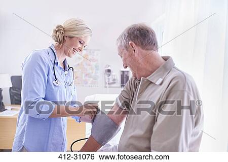 Doctor checking senior mans blood pressure in examination room View Large Photo Image Stock Photograph - Doctor checking senior mans blood pressure in examination room. Fotosearch