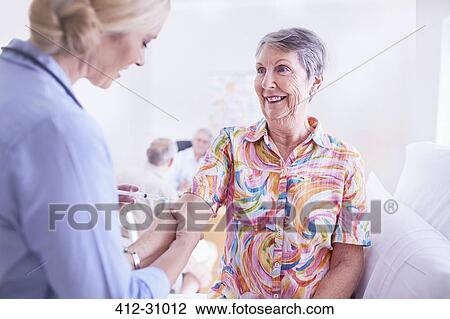 Stock Image - Doctor checking senior womans arm in checkup. Fotosearch