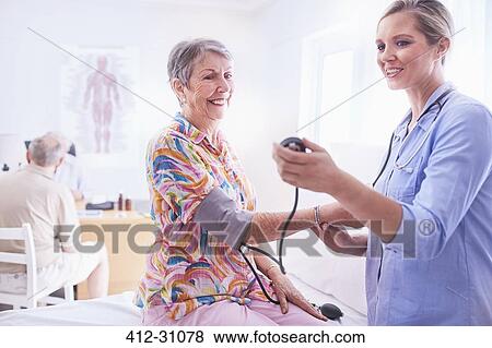 Doctor checking senior womans blood pressure in examination room View Large Photo Image Stock Photo - Doctor checking senior womans blood pressure in examination room. Fotosearch