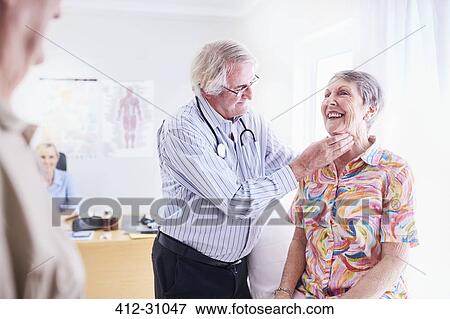 Stock Photo - Doctor checking senior womans glands at checkup. Fotosearch