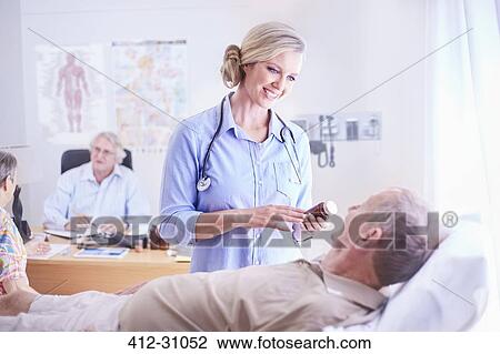 Stock Image - Doctor discussing prescription medication to senior man. Fotosearch