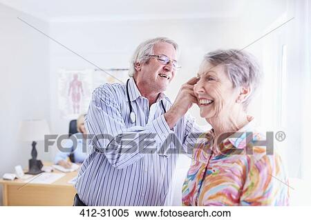 Stock Photography - Doctor examining senior womans ear in checkup. Fotosearch