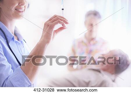 Doctor preparing syringe near senior man View Large Photo Image Stock Photo - Doctor preparing syringe near senior man. Fotosearch