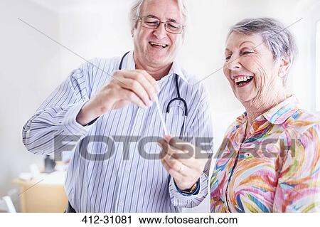 Stock Image - Doctor showing senior woman thermometer. Fotosearch