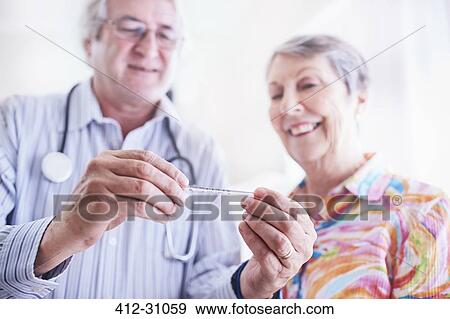 Doctor showing thermometer to senior woman View Large Photo Image Stock Photo - Doctor showing thermometer to senior woman. Fotosearch