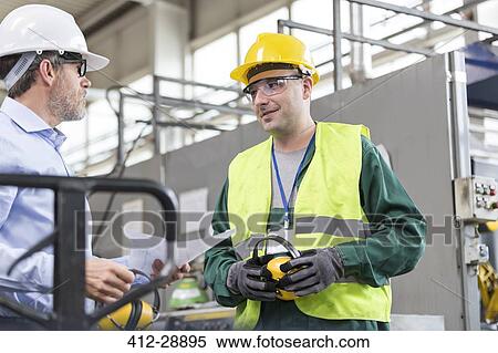 Engineer and worker in protective workwear talking in factory View Large Photo Image Stock Photography - Engineer and worker in protective workwear talking in factory. Fotosearch