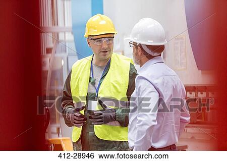 Stock Photograph - Engineer and worker talking in factory. Fotosearch