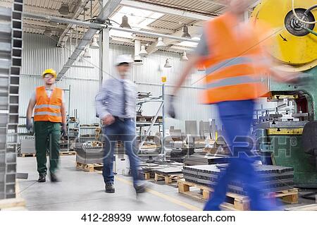 Stock Photo - Engineer and works walking in factory. Fotosearch