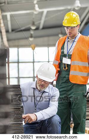 Engineer explaining steel parts to worker in factory View Large Photo Image Stock Image - Engineer explaining steel parts to worker in factory. Fotosearch