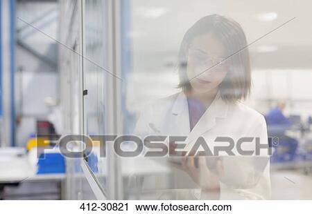 Stock Image - Engineer taking notes on clipboard in steel factory office. Fotosearch