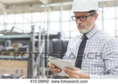 Engineer using digital tablet in factory View Large Photo Image Stock Image - Engineer using digital tablet in factory. Fotosearch