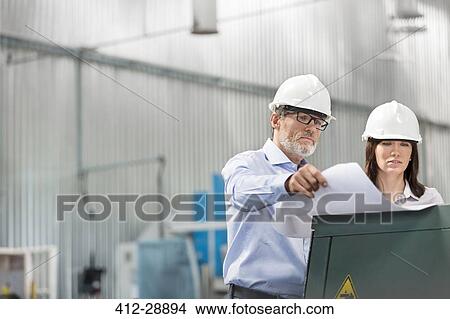 Engineers reviewing blueprints in factory View Large Photo Image Picture - Engineers reviewing blueprints in factory. Fotosearch