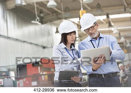 Stock Photograph - Engineers with laptop in factory. Fotosearch