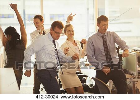 Picture - Enthusiastic business people celebrating and dancing in office. Fotosearch