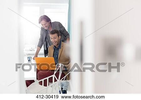 Enthusiastic businessmen using laptop in office View Large Photo Image Stock Photo - Enthusiastic businessmen using laptop in office. Fotosearch