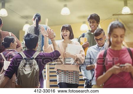 Stock Photograph - Enthusiastic college students high-fiving in stairway. Fotosearch