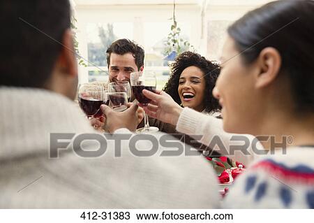 Enthusiastic friends toasting wine glasses at Christmas dinner View Large Photo Image Stock Image - Enthusiastic friends toasting wine glasses at Christmas dinner. Fotosearch
