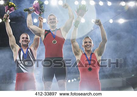 Stock Photo - Enthusiastic male gymnasts celebrating victory on winners podium. Fotosearch