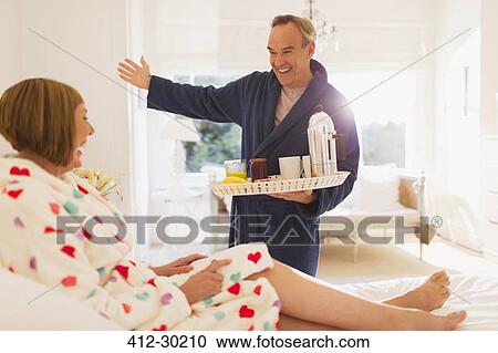 Enthusiastic mature man serving breakfast to wife in bed View Large Photo Image Stock Image - Enthusiastic mature man serving breakfast to wife in bed. Fotosearch